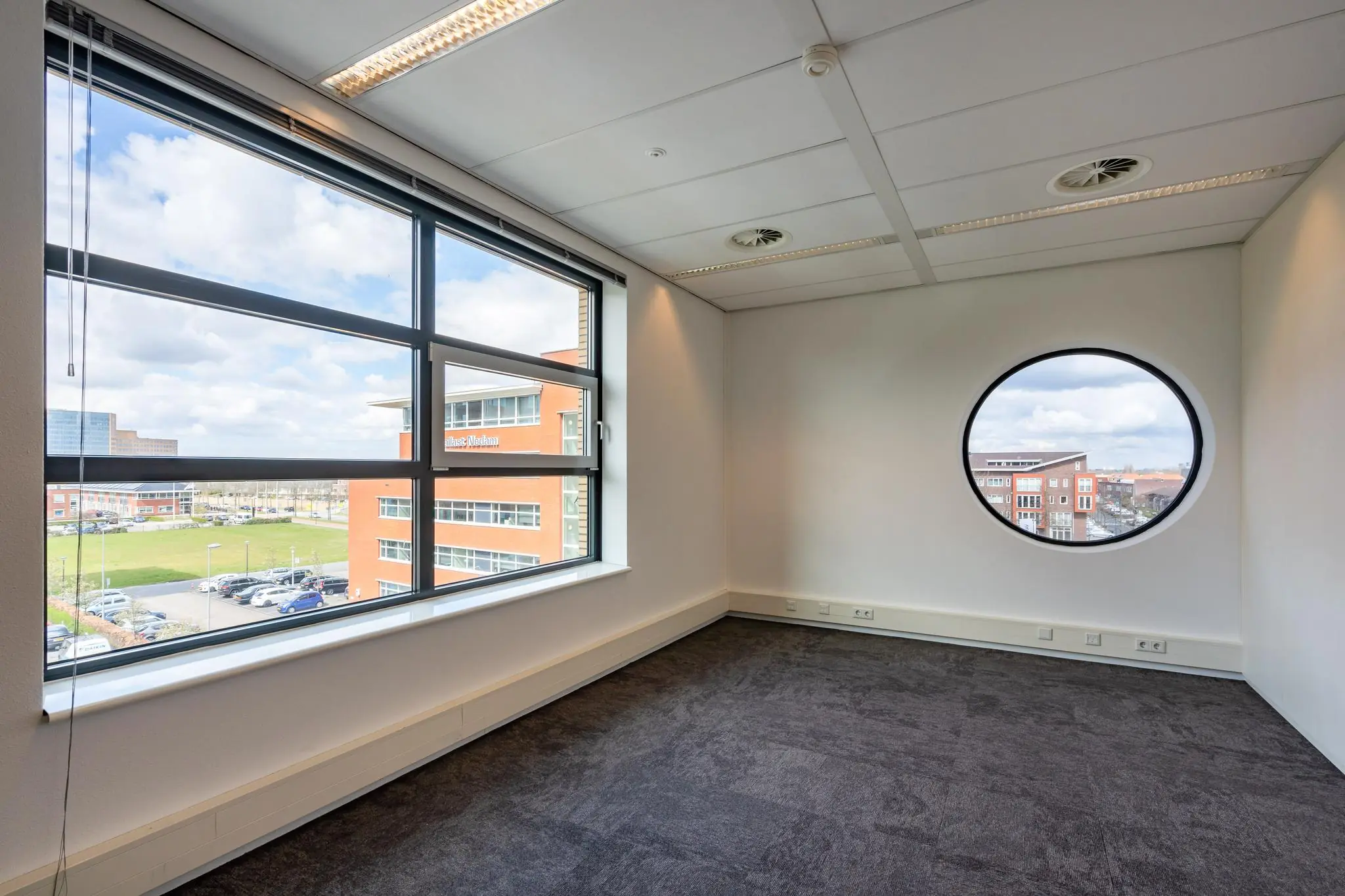 Licht en leeg kantoor met groot rechthoekig en rond raam aan de Fascinatio Boulevard.